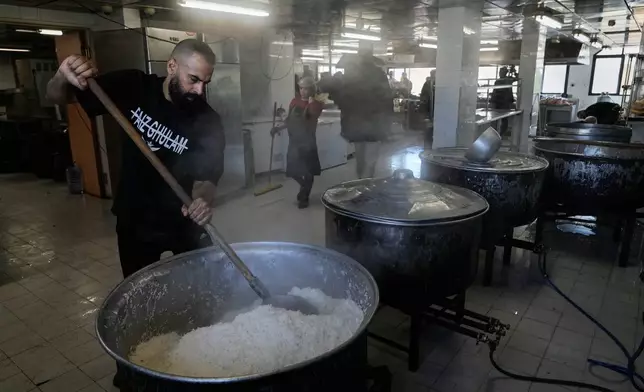 Volunteers cook meals for displaced people who fled Israeli airstrikes in southern Lebanon and Dahiyeh, Beirut's southern suburbs, at the Bir Hassan Technical Institute, which has been turned into a shelter, in Beirut, Lebanon, Wednesday, March 11, 2026. (AP Photo/Bilal Hussein)