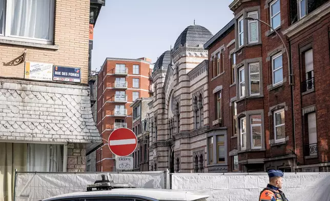 Police stand near a fence as they secure an area after a blast near a synagogue in Liege, Belgium, Monday, March 9, 2026. (AP Photo/Valentin Bianchi)