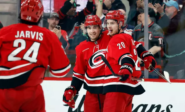 Carolina Hurricanes' Sean Walker, center, celebrates his game winning overtime goal with teammates Sebastian Aho (20) and Seth Jarvis (24) at an NHL hockey game against the Pittsburgh Penguins in Raleigh, N.C., Wednesday, March 18, 2026. (AP Photo/Karl DeBlaker)