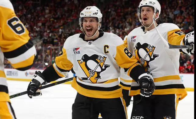 Pittsburgh Penguins' Sidney Crosby (87) comes to congratulate teammate Erik Karlsson, left, on his goal with Rickard Rakell, right, during the third period of an NHL hockey game against the Carolina Hurricanes in Raleigh, N.C., Wednesday, March 18, 2026. (AP Photo/Karl DeBlaker)