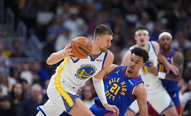 Golden State Warriors forward Kristaps Porziņģis, left, drives past Denver Nuggets forward Spencer Jones in the first half of an NBA basketball game Sunday, March 29, 2026, in Denver. (AP Photo/David Zalubowski)