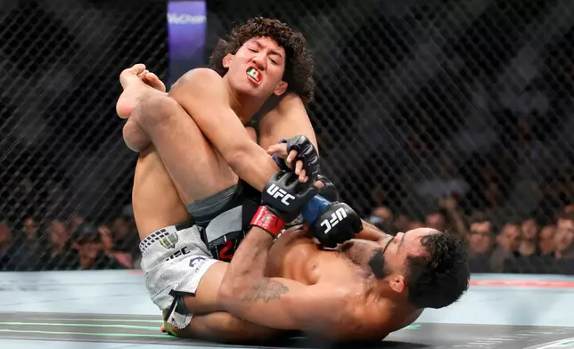 Raul Rosas Jr., top, grapples with Rob Font, bottom, in a bantamweight mixed martial arts bout during UFC 326, Saturday, March 7, 2026, in Las Vegas. (Steve Marcus/Las Vegas Sun via AP)
