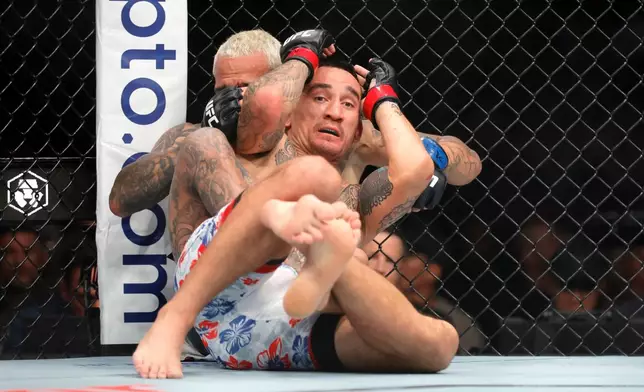 Max Holloway, foreground, grapples with Charles Oliveira in a lightweight fight during UFC 326 Saturday, March 7, 2026, in Las Vegas. (Steve Marcus/Las Vegas Sun via AP)