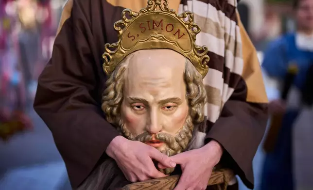 A penitent of the 'Pollinita' brotherhood, dressed in a typical Apostle costume, holds an image symbolizing the apostles during the Holy Week procession in Cabra, southern Spain, Sunday, March 29, 2026. (AP Photo/Manu Fernandez)