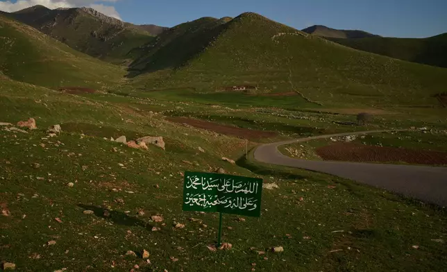 A sign displays a prayer that reads in Arabic: "Oh Allah, send blessings upon our prophet, and upon his family, and companions", on a road near the village of Gulp, Iraq, Tuesday, March 17, 2026. (AP Photo/Leo Correa)