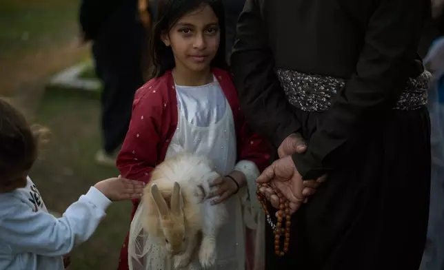 A girl holds her rabbit as she takes part in a family gathering to break the fast with an Iftar meal during the Muslim holy month of Ramadan in the village of Gulp, Iraq, Tuesday, March 17, 2026. (AP Photo/Leo Correa)