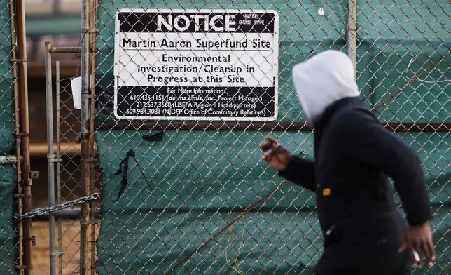 FILE - A man walks past a notice for the Martin Aaron Inc. Superfund site in Camden, N.J., Dec. 11, 2017. (AP Photo/Matt Rourke, File)