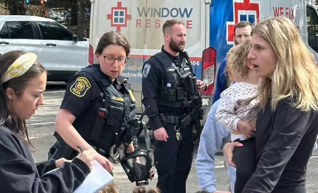 A woman gathers children as law enforcement respond to a call at Temple Israel synagogue on Thursday, March 12, 2026, in West Bloomfield Township, Mich. (AP Photo/Corey Williams)