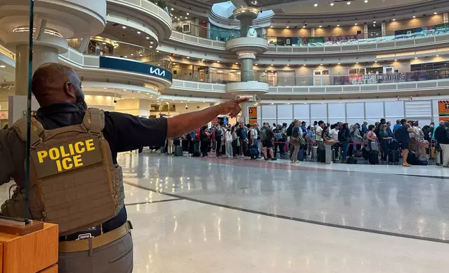 A federal immigration agent is seen as people wait in a TSA line at the Hartsfield-Jackson Atlanta International Airport, Monday, March 23, 2026, in Atlanta. (AP Photo/Emilie Megnien)
