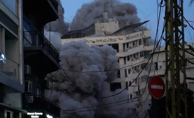 A building collapses as smoke rises following an Israeli strike in central Beirut, Lebanon, Wednesday, March 18, 2026. (AP Photo/Hussein Malla)