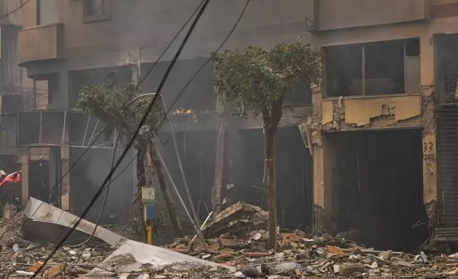 Debris litters the street as smoke rises from buildings damaged in an Israeli airstrike in Dahiyeh, Beirut's southern suburbs, Lebanon, Sunday, March 15, 2026. (AP Photo/Hassan Ammar)