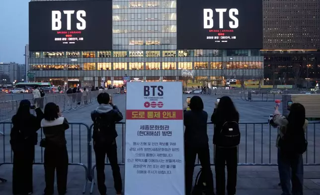 People take photos of screens promoting a comeback concert of K-pop group BTS at Gwanghwamun Square in Seoul, March 17, 2026. (AP Photo/Ahn Young-joon)