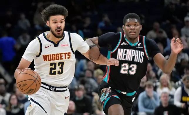 Denver Nuggets forward Cameron Johnson, left, handles the ball against Memphis Grizzlies forward Cedric Coward in the first half of an NBA basketball game Wednesday, March 18, 2026, in Memphis, Tenn. (AP Photo/Brandon Dill)