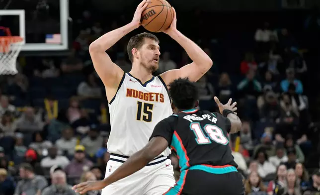 Denver Nuggets center Nikola Jokic (15) handles the ball against Memphis Grizzlies forward Olivier-Maxence Prosper (18) in the first half of an NBA basketball game Wednesday, March 18, 2026, in Memphis, Tenn. (AP Photo/Brandon Dill)