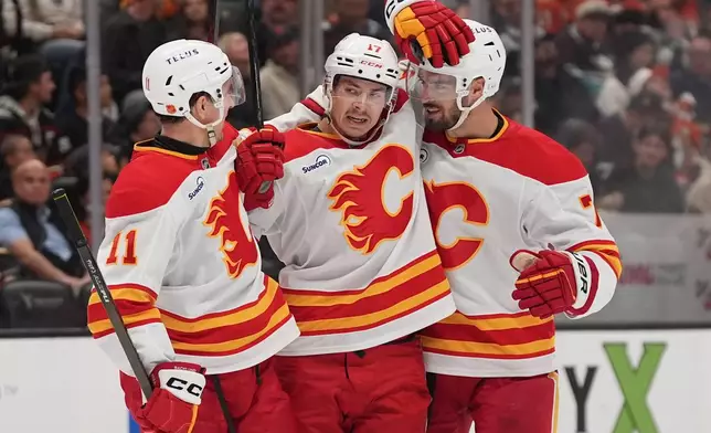 Calgary Flames center Yegor Sharangovich, center, celebrates his goal with teammates center Mikael Backlund (11) and defenseman Kevin Bahl, right, during the second period of an NHL hockey game against the Anaheim Ducks Sunday, March 1, 2026, in Anaheim, Calif. (AP Photo/Gregory Bull)