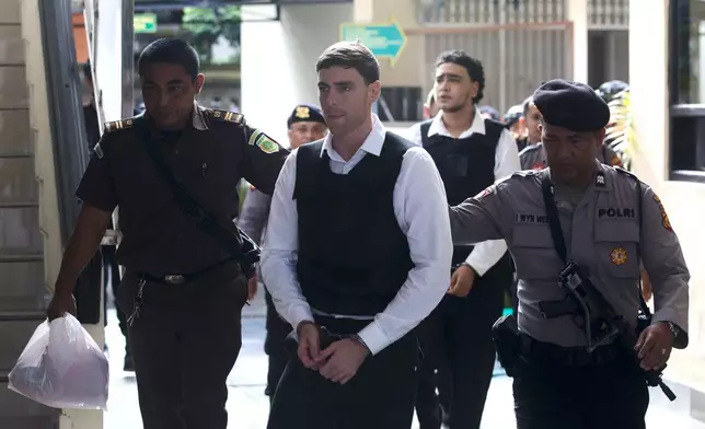 Australian nationals Darcy Jenson, foreground center, and Mevlut Coskun, rear, who are on trial in the fatal shooting of an Australian tourist last year, are escorted by police officers after their sentencing hearing at the district court, in Denpasar, Bali, Indonesia, Monday, March 9, 2026. (AP Photo/Firdia Lisnawati)