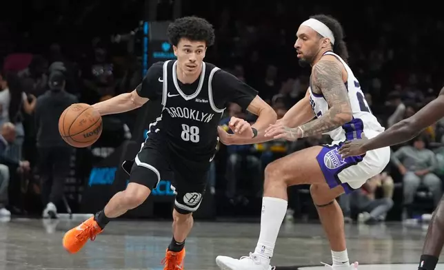 Brooklyn Nets' Nolan Traore (88) drives past Sacramento Kings' Devin Carter (22) during the second half of an NBA basketball game Sunday, March 29, 2026, in New York. (AP Photo/Frank Franklin II)