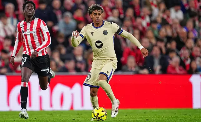 Barcelona's Lamine Yamal, center, dribbles the ball followed by Athletic Bilbao's Adama Boiro during the Spanish La Liga soccer match between Athletic Bilbao and Barcelona in Bilbao, Spain, Saturday, March 7, 2026. (AP Photo/Miguel Oses)