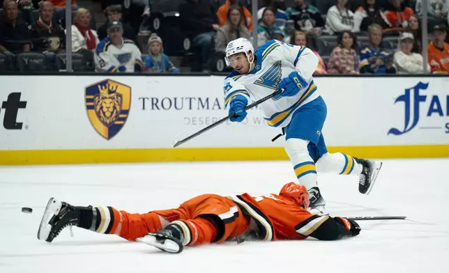 St. Louis Blues right wing Jordan Kyrou, top, shoots to score past the slide by Anaheim Ducks defenseman Ian Moore during the second period of an NHL hockey game, Sunday, March 8, 2026, in Anaheim, Calif. (AP Photo/Kyusung Gong)