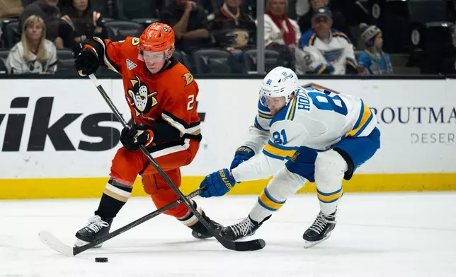 Anaheim Ducks defenseman Jackson LaCombe controls the puck away from St. Louis Blues left wing Dylan Holloway during the second period of an NHL hockey game, Sunday, March 8, 2026, in Anaheim, Calif. (AP Photo/Kyusung Gong)