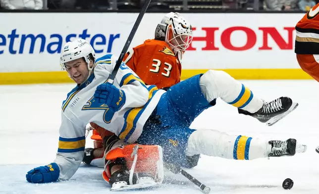 St. Louis Blues right wing Jimmy Snuggerud, front, skates into Anaheim Ducks goaltender Ville Husso during the second period of an NHL hockey game, Sunday, March 8, 2026, in Anaheim, Calif. (AP Photo/Kyusung Gong)