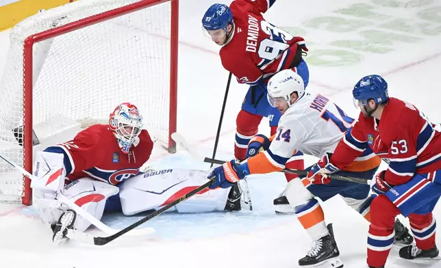 Montreal Canadiens' Ivan Demidov (93) and Noah Dobson (53) defend against New York Islanders' Bo Horvat (14) as he moves in on Canadiens goaltender Jacob Fowler (32) during the second period of an NHL hockey game in Montreal, Saturday, March 21, 2026. (Graham Hughes/The Canadian Press via AP)