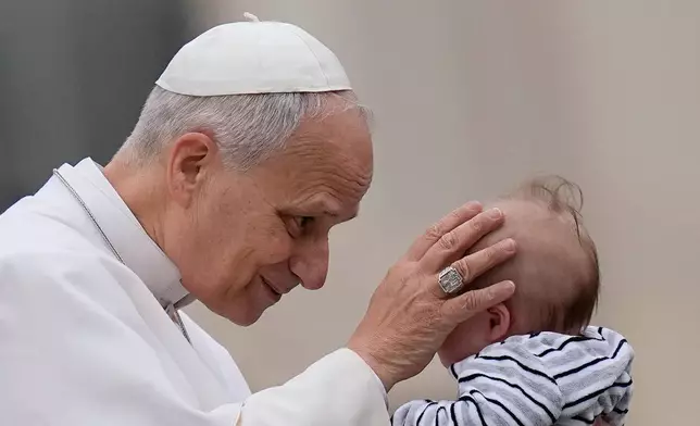 Pope Leo XIV blesses a child at the end of his weekly general audience in St. Peter's Square, at the Vatican, Wednesday, March 4, 2026. (AP Photo/Alessandra Tarantino)