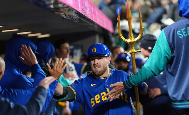 Seattle Mariners' Luke Raley celebrates with the trident in the dugout after hitting a two-run home run against the Cleveland Guardians during the sixth inning of a baseball game, Friday, March 27, 2026, in Seattle. (AP Photo/Lindsey Wasson)