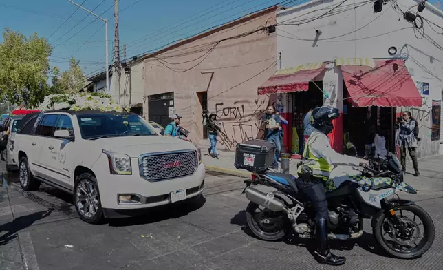 A police officer escorts the car carrying the remains of who authorities identified as the late Jalisco New Generation Cartel leader Nemesio Oseguera, alias "El Mencho," to Recinto de Paz cemetery for burial in Guadalajara, Mexico, Monday, March 2, 2026. (AP Photo/Refugio Ruiz)