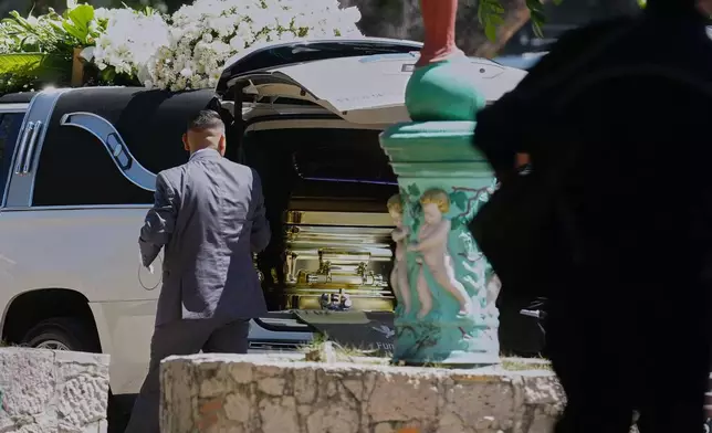 A funeral worker opens the door of a car carrying the remains of who authorities identified as the late Jalisco New Generation Cartel leader Nemesio Oseguera, alias "El Mencho," at Recinto de Paz cemetery in Guadalajara, Mexico, Monday, March 2, 2026. (AP Photo/Refugio Ruiz)