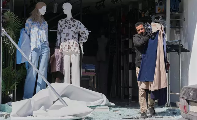 A man removes clothes from his damaged shop at a commercial street that was hit by an Israeli airstrike in Nabatiyeh town, south Lebanon, Thursday, March 5, 2026. (AP Photo/Mohammed Zaatari)