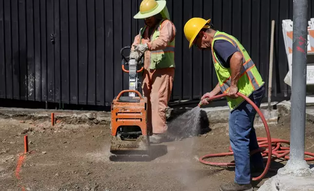 Construction workers spray water during an unseasonably hot day at MacArthur Park on Thursday, Mar. 12, 2026 in Los Angeles. (AP Photo/Ryan Sun)