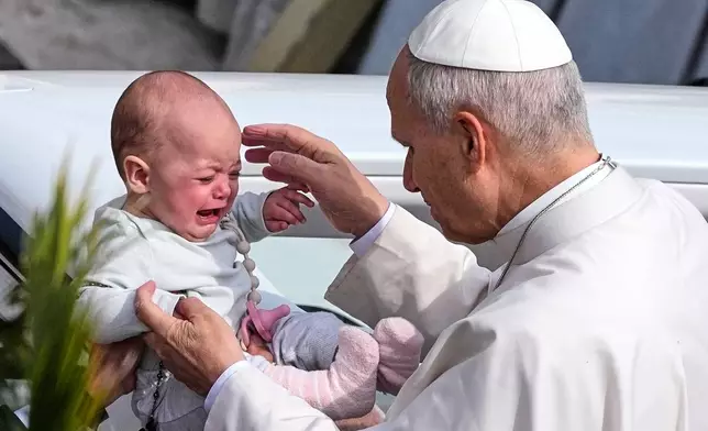 Pope Leo XIV caresses a child after presiding over Mass in St. Peter's Square at the Vatican on the Catholic feast of Palm Sunday, commemorating Jesus' arrival in Jerusalem, Sunday, March 29, 2026. (AP Photo/Alessandra Tarantino)