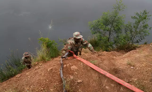 South African National Defense Force soldiers recover a generator left behind by illegal miners, during a patrol in Randfontein, in Johannesburg, South Africa, Thursday, March 12, 2026. (AP Photo/Themba Hadebe)