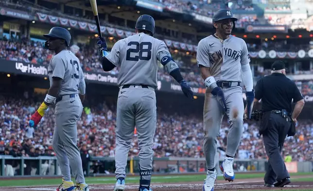 New York Yankees' Jazz Chisholm Jr., left, and José Caballero, right, are congratulated by Austin Wells (28) after both scored on Ryan McMahon's two-run single against the San Francisco Giants during the second inning of a baseball game in San Francisco, Wednesday, March 25, 2026. (AP Photo/Jeff Chiu)