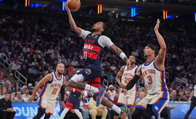 Washington Wizards' Sharife Cooper (13) drives past New York Knicks' Josh Hart (3) and Jalen Brunson (11) during the second half of an NBA basketball game Sunday, March 22, 2026, in New York. (AP Photo/Frank Franklin II)