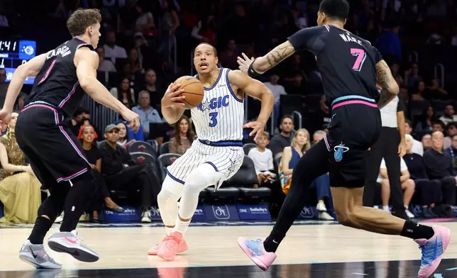 Miami Heat guard Pelle Larsson (9) and Miami Heat Kel'el Ware (7) defend Orlando Magic guard Desmond Bane (3) during the first half of an NBA basketball game in Miami, Saturday, March 14, 2026. (AP Photo/Rhona Wise)
