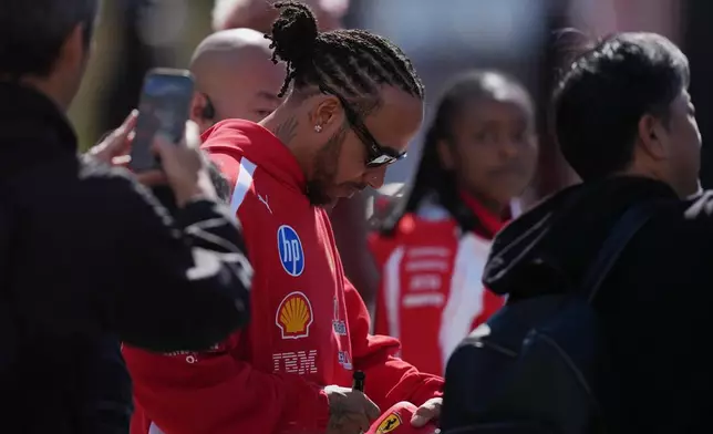 Ferrari driver Lewis Hamilton of Britain gives an autograph in Suzuka, central Japan, Thursday, March 26, 2026, ahead of Sunday's Japanese Formula One Grand Prix race. (AP Photo/Hiro Komae)
