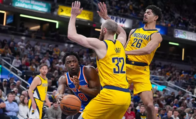 New York Knicks guard OG Anunoby (8) makes a pass around Indiana Pacers center Jay Huff (32) during the first half of an NBA basketball game in Indianapolis, Friday, March 13, 2026. (AP Photo/Michael Conroy)