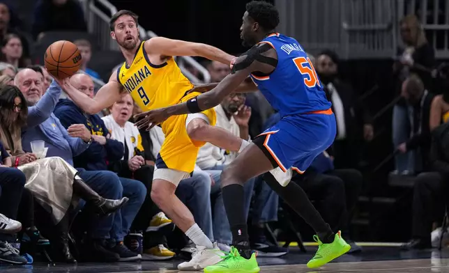 Indiana Pacers guard T.J. McConnell (9) makes a save in front of New York Knicks forward Mohamed Diawara (51) during the first half of an NBA basketball game in Indianapolis, Friday, March 13, 2026. (AP Photo/Michael Conroy)