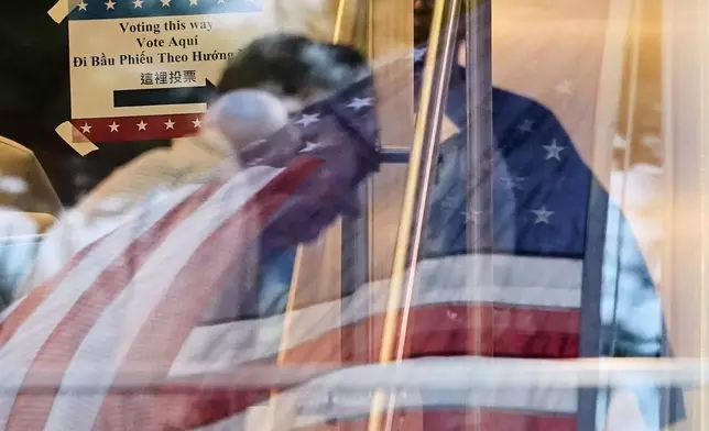 A voter makes his way inside a polling location, where a U.S. flag is reflected on the windows, Tuesday, March 3, 2026, in Spring, Texas. (AP Photo/David J. Phillip)