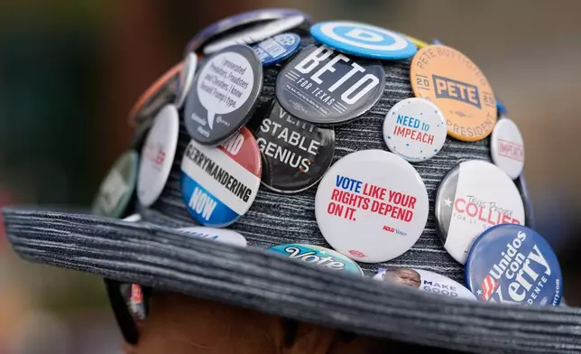 Pat Garris wears a hat full of political buttons outside a polling location Tuesday, March 3, 2026, in Spring, Texas. (AP Photo/David J. Phillip)