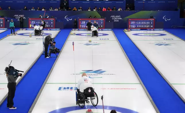 Steve Emt, foreground, and Laura Dwyer, center, of the United States, compete against Yoji Nakajima and Aki Ogawa, of Japan, in a wheelchair curling mixed doubles round robin session at the 2026 Winter Paralympics, in Cortina d'Ampezzo, Italy, Thursday, March 5, 2026. (AP Photo/Evgeniy Maloletka)
