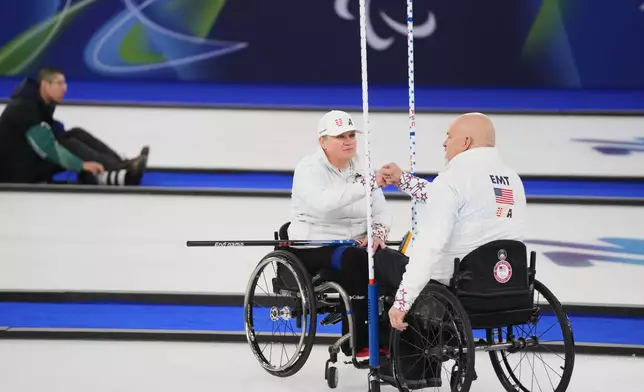 Steve Emt, right, and Laura Dwyer, of the United States, bump fists during their wheelchair curling mixed doubles round robin session against Japan at the 2026 Winter Paralympics, in Cortina d'Ampezzo, Italy, Thursday, March 5, 2026. (AP Photo/Evgeniy Maloletka)