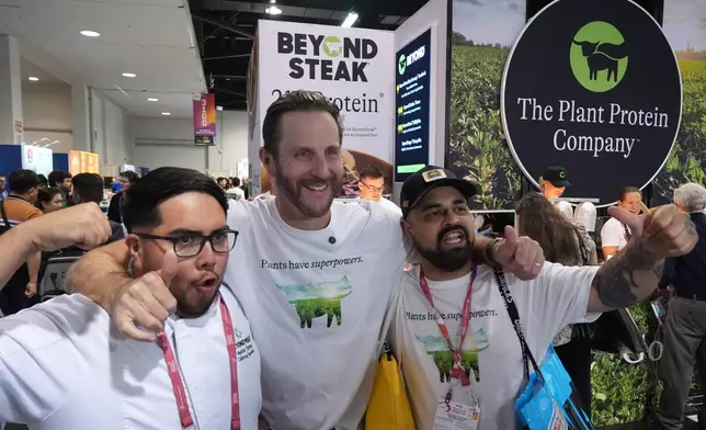 Beyond CEO Ethan Brown, the company's founder, center, with Beyond Meat, kitchen assistant, Hector Torres, left, and Antonio Partida, Sr. Kitchen Prep, right, poses for a photo at their Beyond booth as the company is transitioning from Beyond Meat to just Beyond, to introduce a new line of sparkling plant‑protein drinks at the Natural Products Expo West 2026 at the Anaheim Convention Center in Anaheim, Calif., on Thursday, March 5, 2026. (AP Photo/Damian Dovarganes)