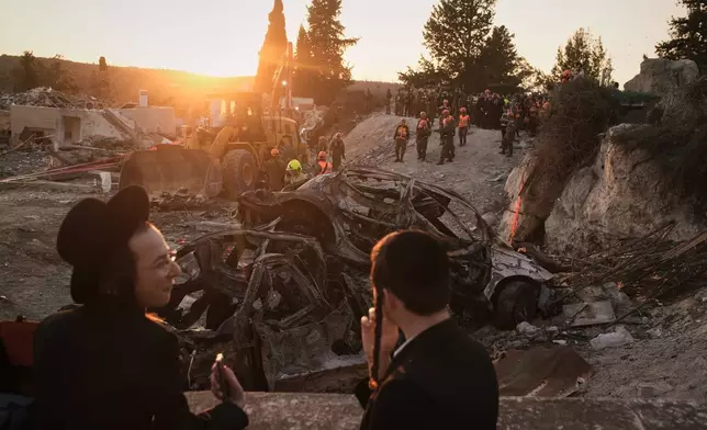 Ultra-Orthodox Jewish men look on as Israeli security forces operate at the site where several people were killed in an Iranian missile strike in Beit Shemesh, Israel, Sunday, March 1, 2026. (AP Photo/Leo Correa)