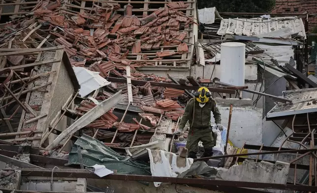 An officer from Israel's Home Front Command searches through the rubble of a destroyed house after it was struck by an Iranian missile in Beit Shemesh, Israel, Sunday, March 1, 2026. (AP Photo/Leo Correa)