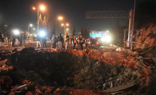Israeli security forces inspect a damaged road after a missile launched from Iran struck Jerusalem, Sunday, March 1, 2026.(AP Photo/Mahmoud Illean)