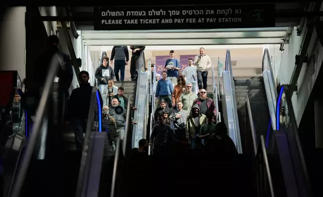 People take shelter in an underground parking garage as air raid sirens warn of incoming missiles launched by Iran toward Tel Aviv, Israel, Sunday, March 1, 2026. (AP Photo/Ohad Zwigenberg)