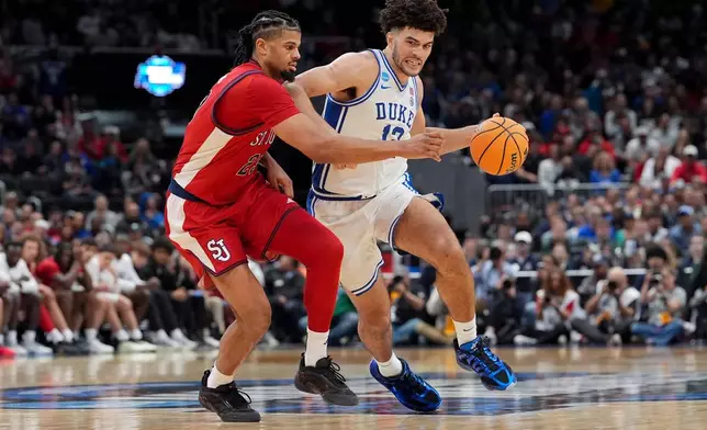 Duke forward Cameron Boozer (12) drives as St. John's forward Bryce Hopkins (23) defends during the second half in the Sweet 16 of the NCAA college basketball tournament, Friday, March 27, 2026, in Washington. (AP Photo/Stephanie Scarbrough)